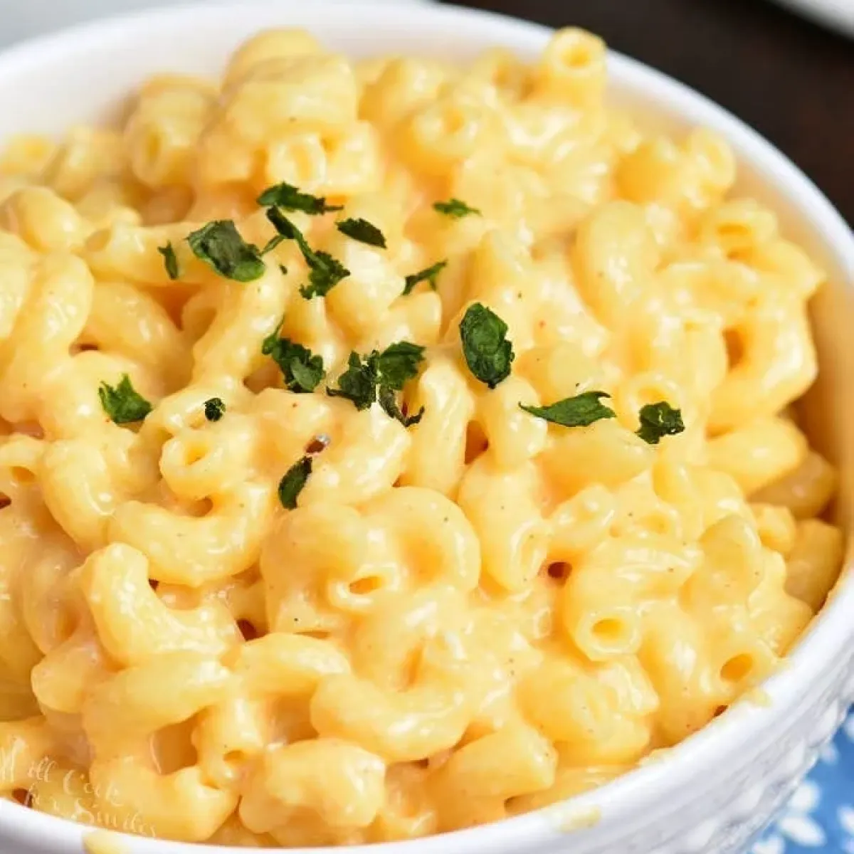 Bowl of creamy macaroni and cheese topped with herbs.