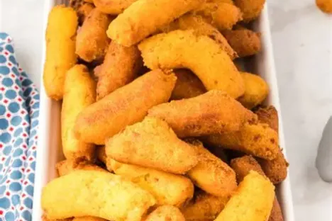 Plate of fried hushpuppies on a table with a patterned napkin nearby.