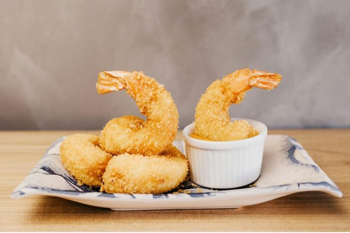 Plate with fried shrimp and dipping sauce on a table.