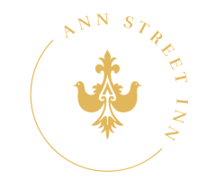 Ann Street Inn logo with two stylized birds and ornate design in yellow circle.