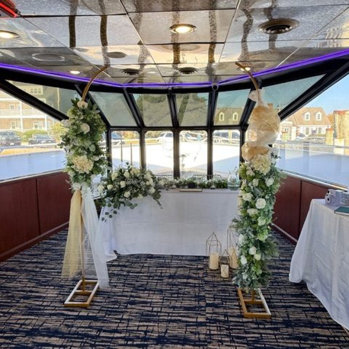 Boat interior with floral wedding arch and decorated table.
