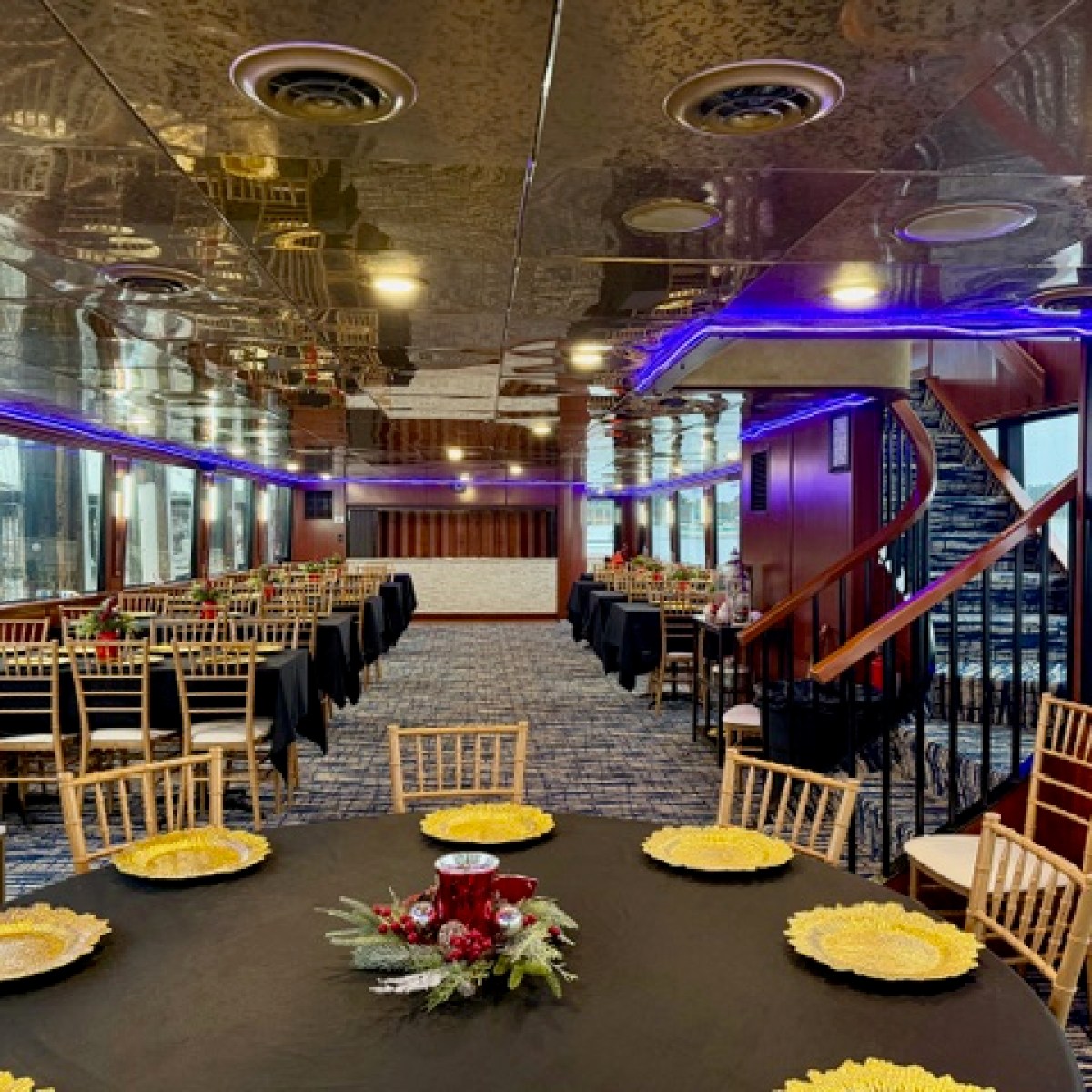 Interior of a dining room with tables, gold plates, and blue lighting, featuring a spiral staircase.