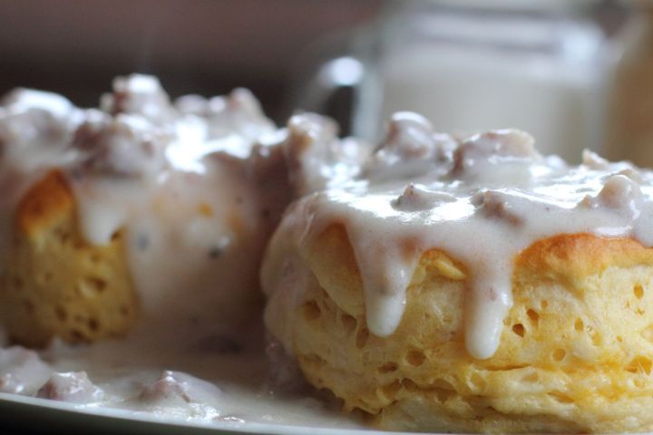Close-up of two biscuits with sausage gravy on a plate.