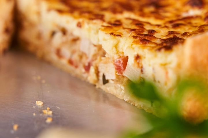 Close-up of a sliced quiche with visible filling on a metal plate.