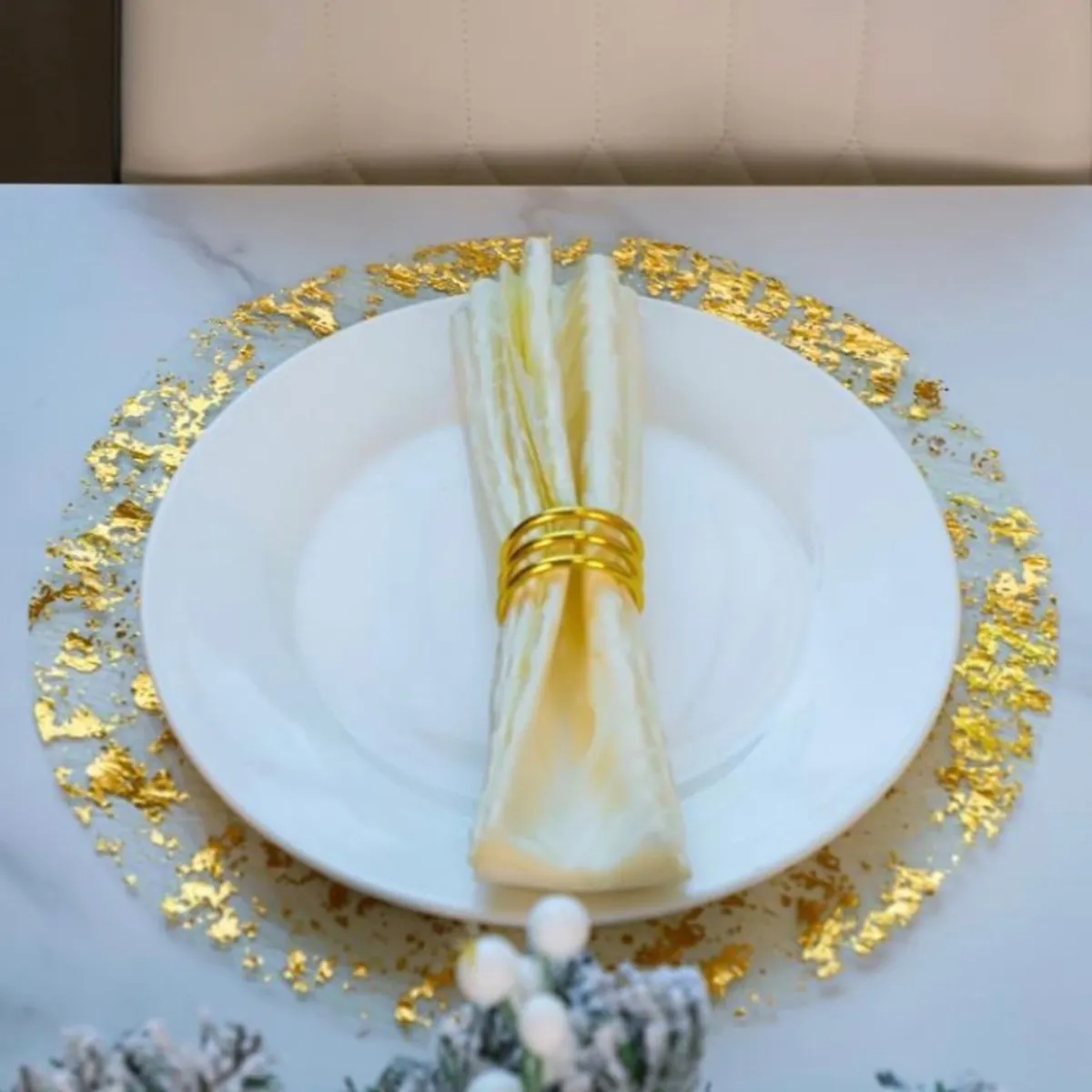 Elegant table setting with a white plate, napkin, and gold accents on a marble surface.