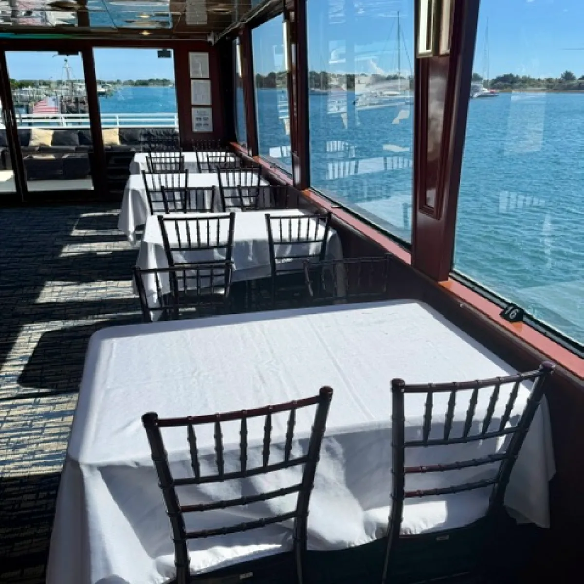 Sunlit, empty dining area with window views of water.